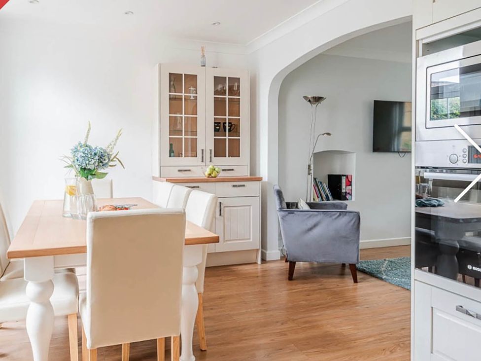 A kitchen with a dining table and chairs and cupboard at 3 bedroom house 3mins to beach PetsOk in Milford On Sea
