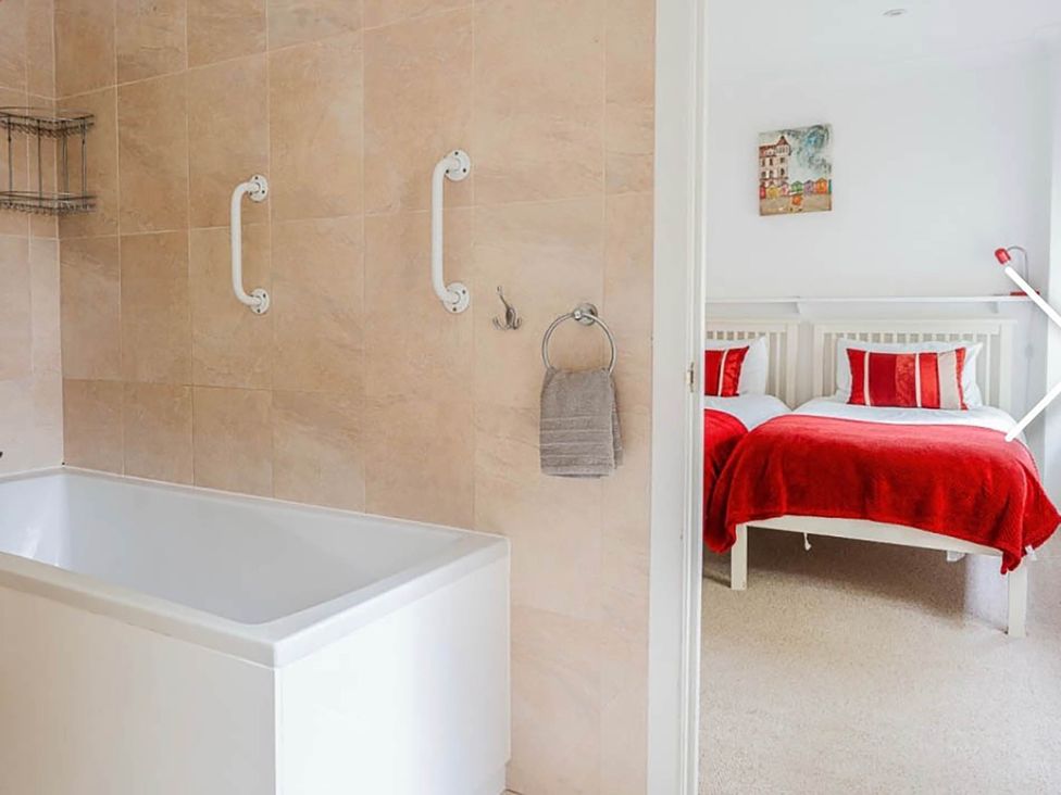 A bathroom with a bathtub and grab bars at 3 bedroom house 3mins to beach PetsOk in Milford On Sea
