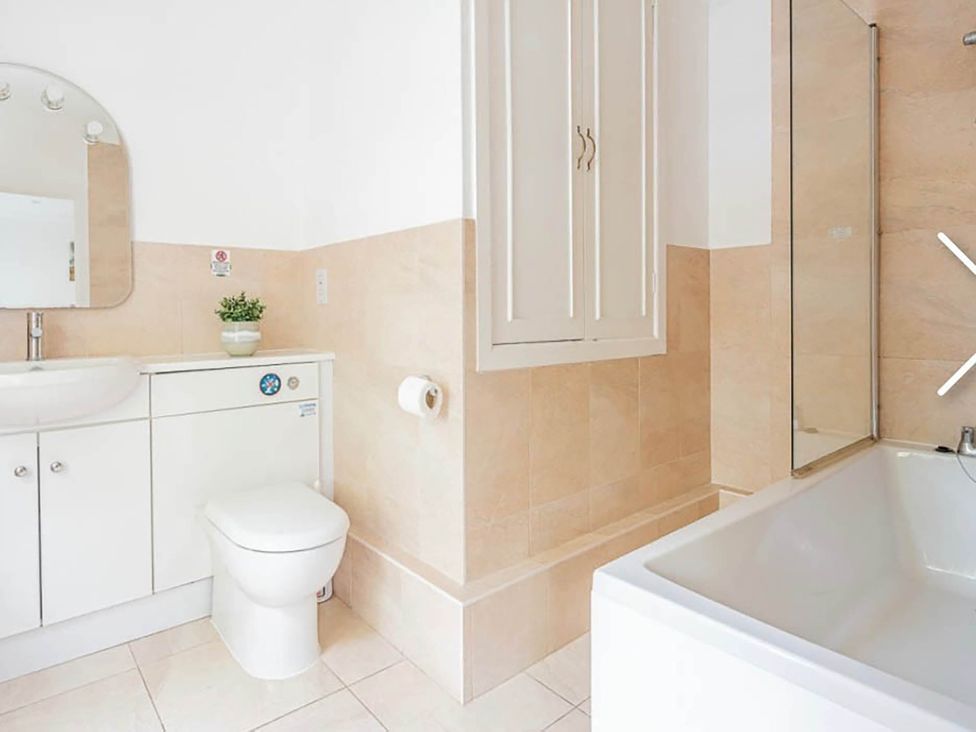 A bathroom with a sink, toilet, bath tub, and mirror at 3 bedroom house 3mins to beach PetsOk in Milford On Sea