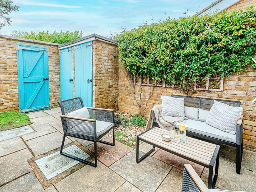 A garden with a sofa, chair, and blue doors at 3 bedroom house 3mins to beach PetsOk in Milford On Sea