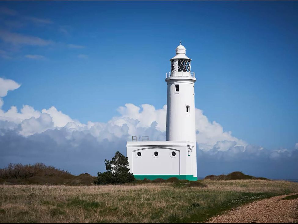 A lighthouse surrounded by grass and clouds at 3 bedroom house 3mins to beach PetsOk Milford On Sea