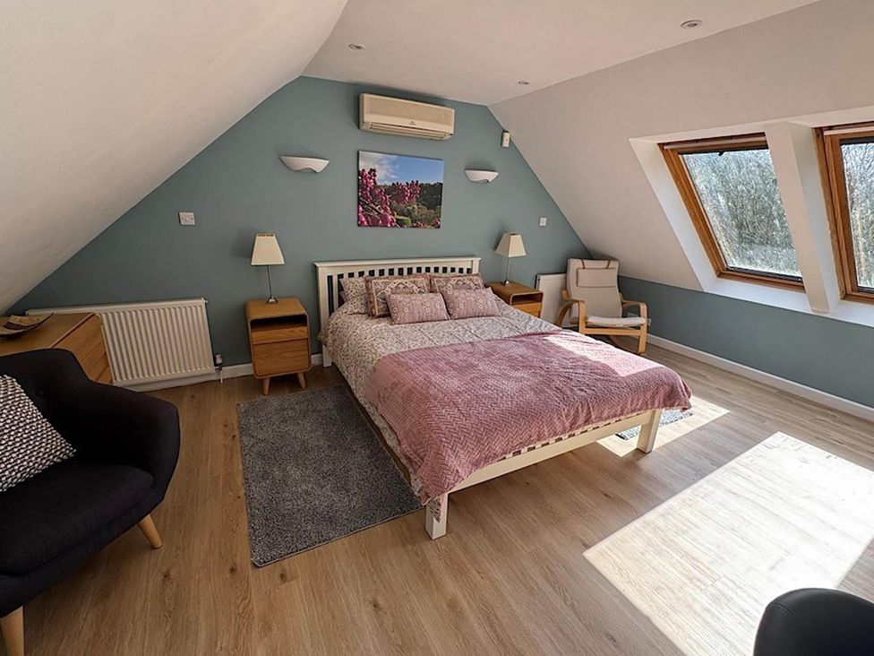 A bedroom with a bed and windows at River Tamar Couples Retreat Dog Friendly in Newbridge