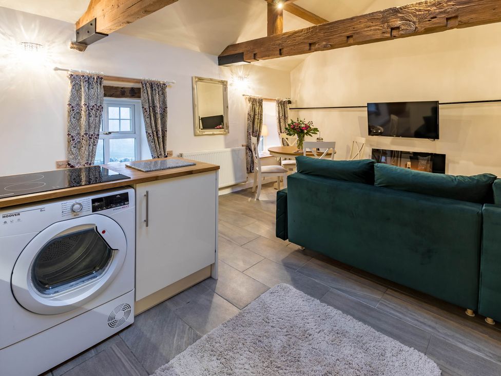 A living room with a washing machine and dining table at The Stables at Brambles Farm Sleeps 2 Wifi, Leek