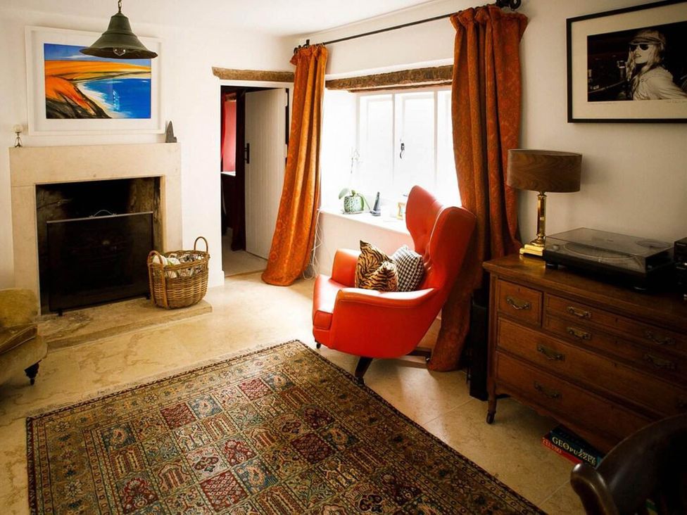 A living room with a fireplace and a red chair at Cotswolds AoNB Cottage Modern Renovation Sleeps8 Combe Hay Lane near Bath