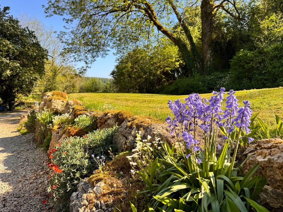 A garden with flowers and a stone wall at Cotswolds AoNB Cottage Modern Renovation Sleeps8 near Combe Hay Lane near Bath