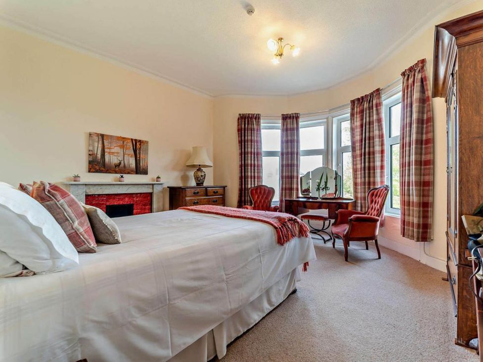 A bedroom with a bed, lamp, fireplace and chairs at Dunoon Sleeps 17 Group Retreat with Parking Kirn near Dunoon