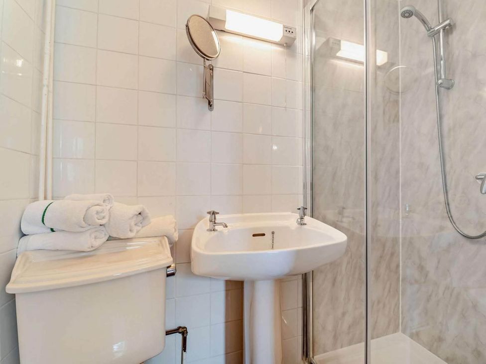 A bathroom with a sink, shower, and towels at Dunoon Sleeps 17 Group Retreat with Parking Kirn near Dunoon