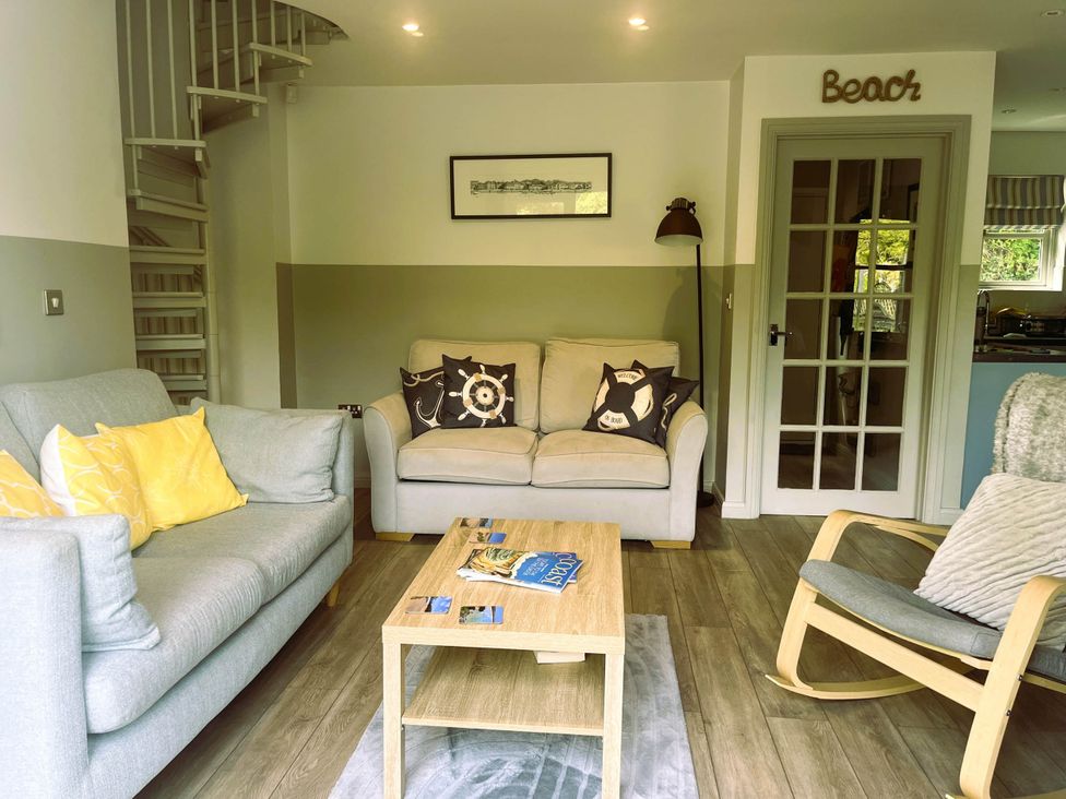 A living room with a sofa, armchair, coffee table, and spiral staircase at 2 Bedrooms overlooking Little Petherick Creek in Little Petherick