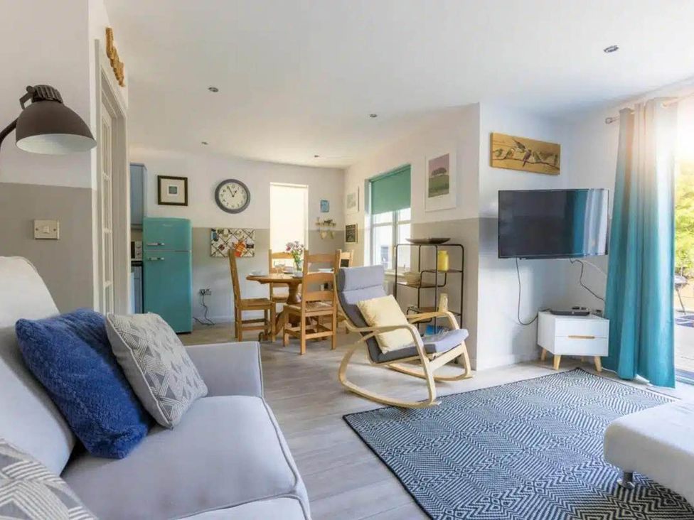 A living room with a television and dining table at 2 Bedrooms overlooking Little Petherick Creek in Little Petherick