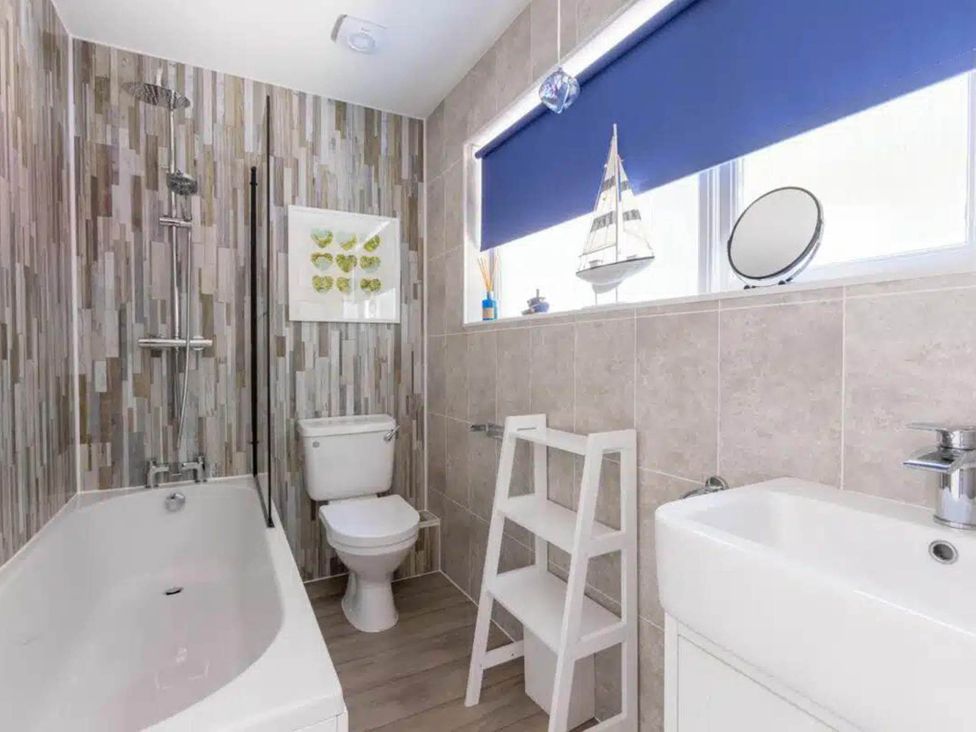 A bathroom featuring a bathtub, toilet, sink, and storage shelf at 2 Bedrooms overlooking Little Petherick Creek in Little Petherick