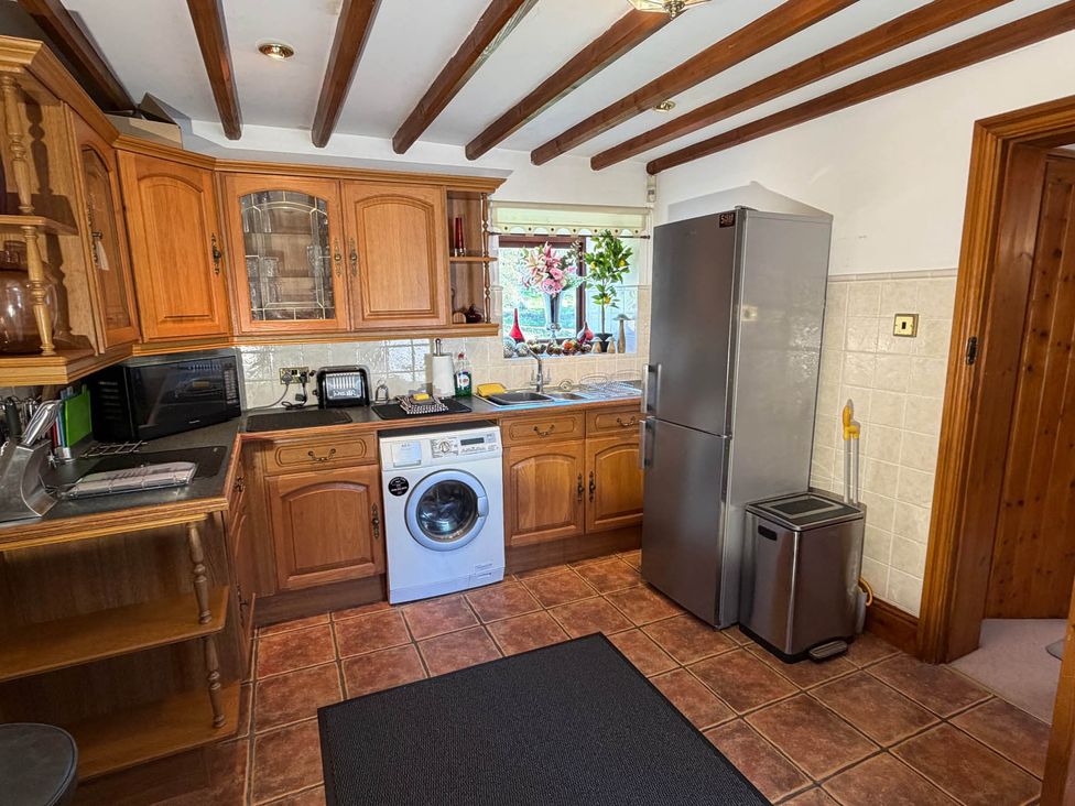 A kitchen with wooden cabinets and appliances at The Old Barn in Whiston near Cheadle