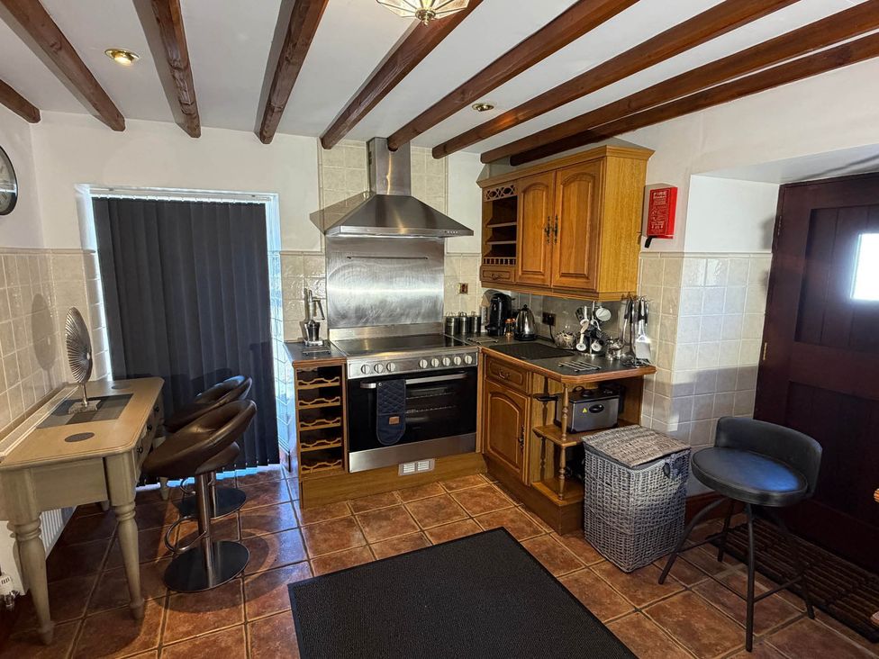 A kitchen with an oven and bar stools at The Old Barn in Whiston near Cheadle