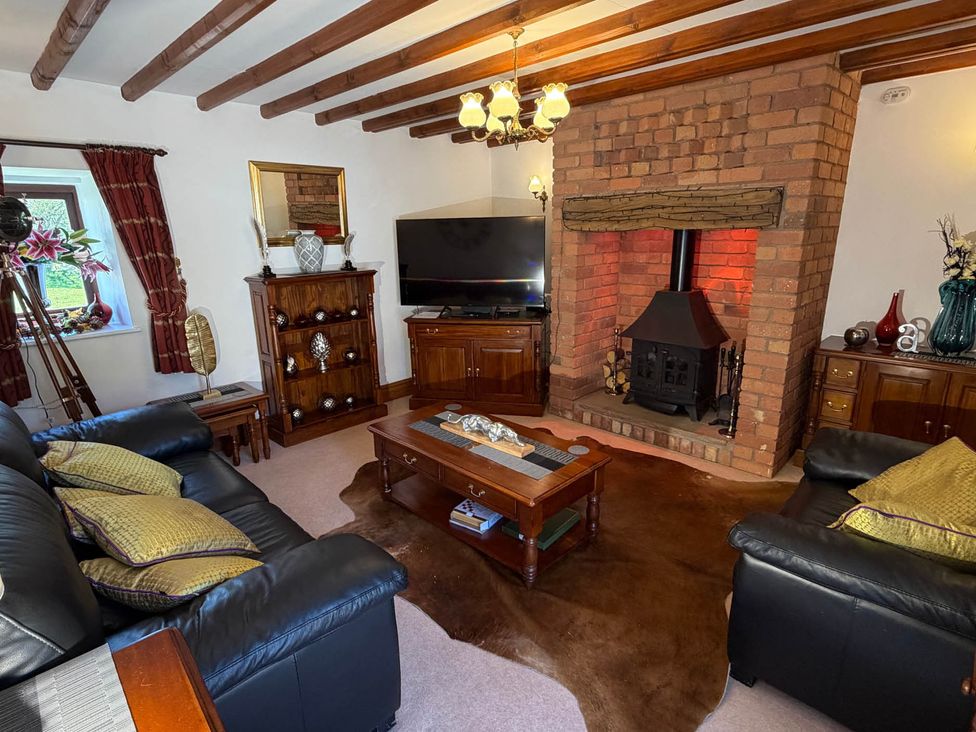 A living room with a brick fireplace and television at The Old Barn in Whiston near Cheadle