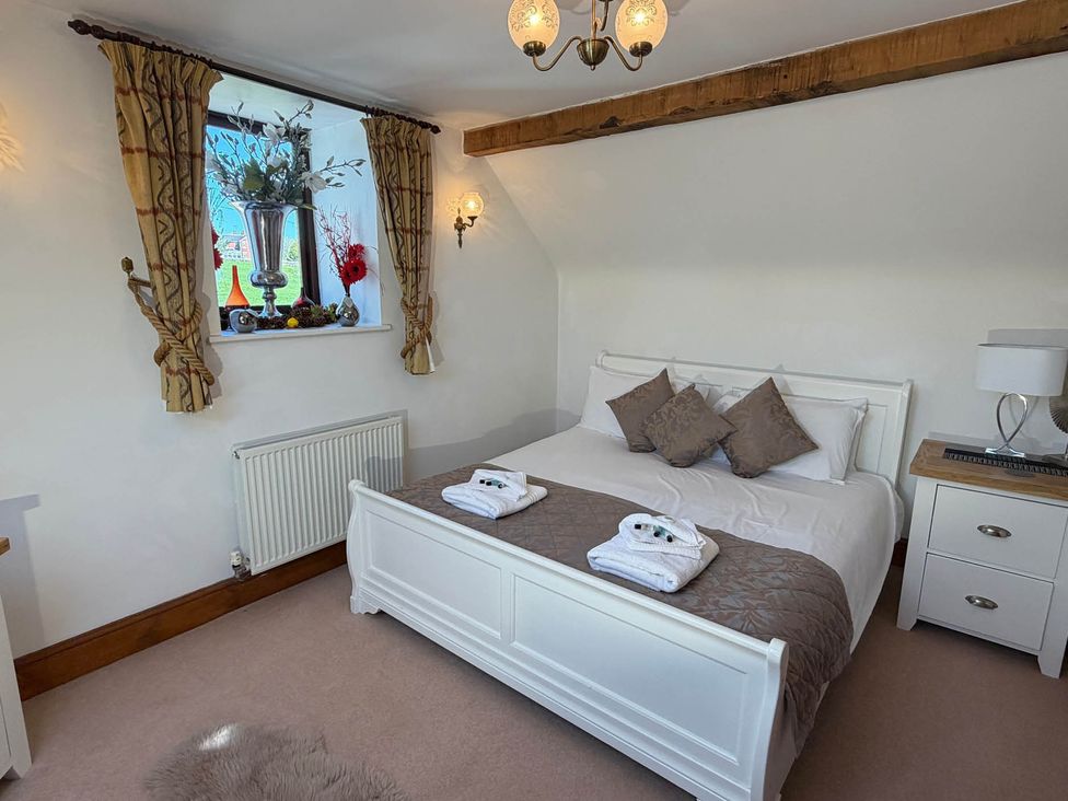 A bedroom with a bed and bedside table at The Old Barn in Whiston near Cheadle