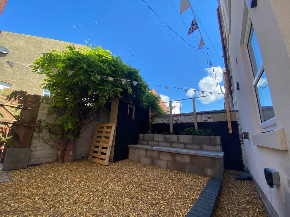 A garden with gravel, a pallet, and flag bunting at Blackpool 4 Beds Sleeps 10 Pet Friendly in Blackpool