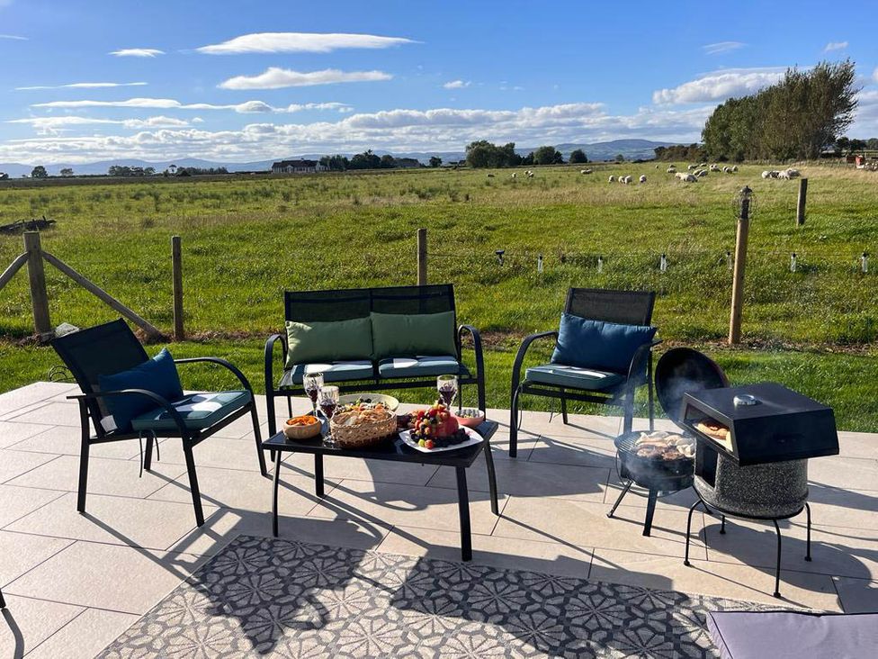 An outdoor seating area with chairs and a barbecue at Sunset Cottage Sleeps 6 with Parking Garden Magilligan near Limavady