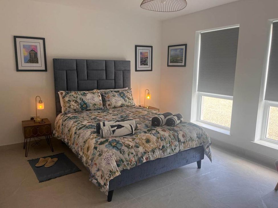 A bedroom with a bed and bedside table at Sunset Cottage Sleeps 6 with Parking Garden in Magilligan near Limavady