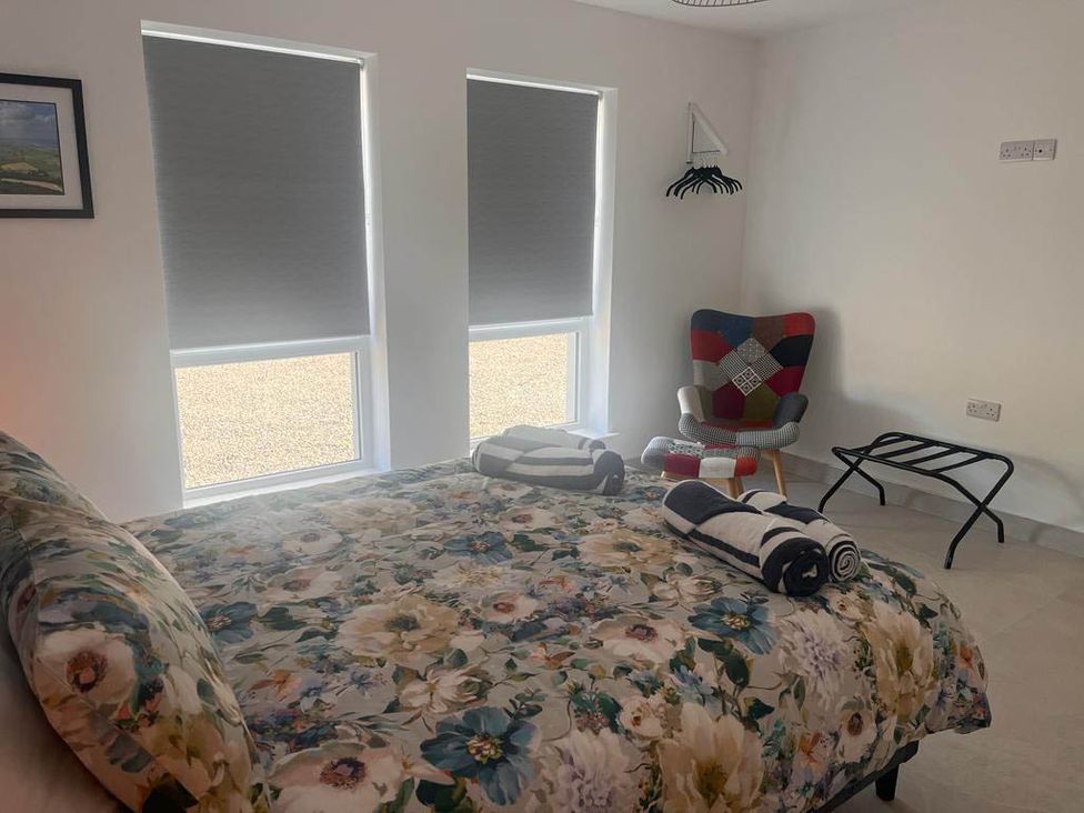 A bedroom with a bed and chair at Sunset Cottage Sleeps 6 with Parking Garden in Magilligan near Limavady
