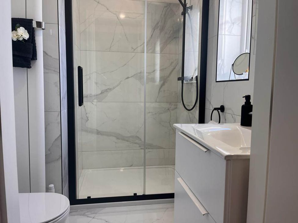 A bathroom with a shower, sink, and toilet at Sunset Cottage Sleeps 6 with Parking Garden in Magilligan near Limavady