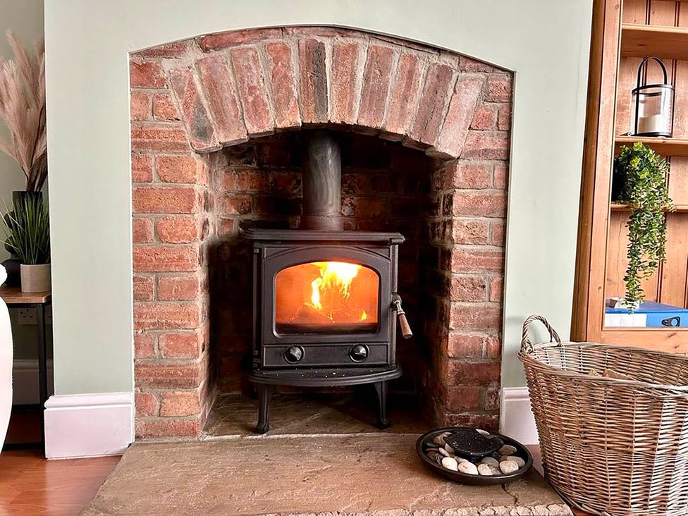 A fireplace with a wood stove and basket of stones at 6 Guests 3Bed House in Chester-Le-Street