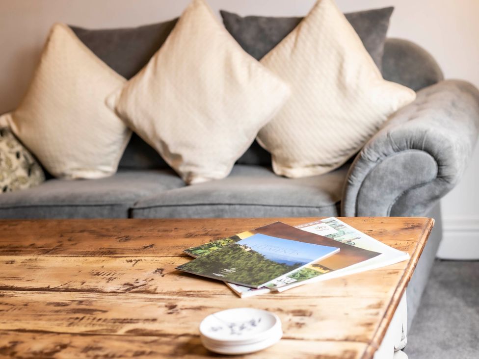 A living room with a sofa and magazines on a coffee table at Cozy Nook boutique Cottage in Oakham