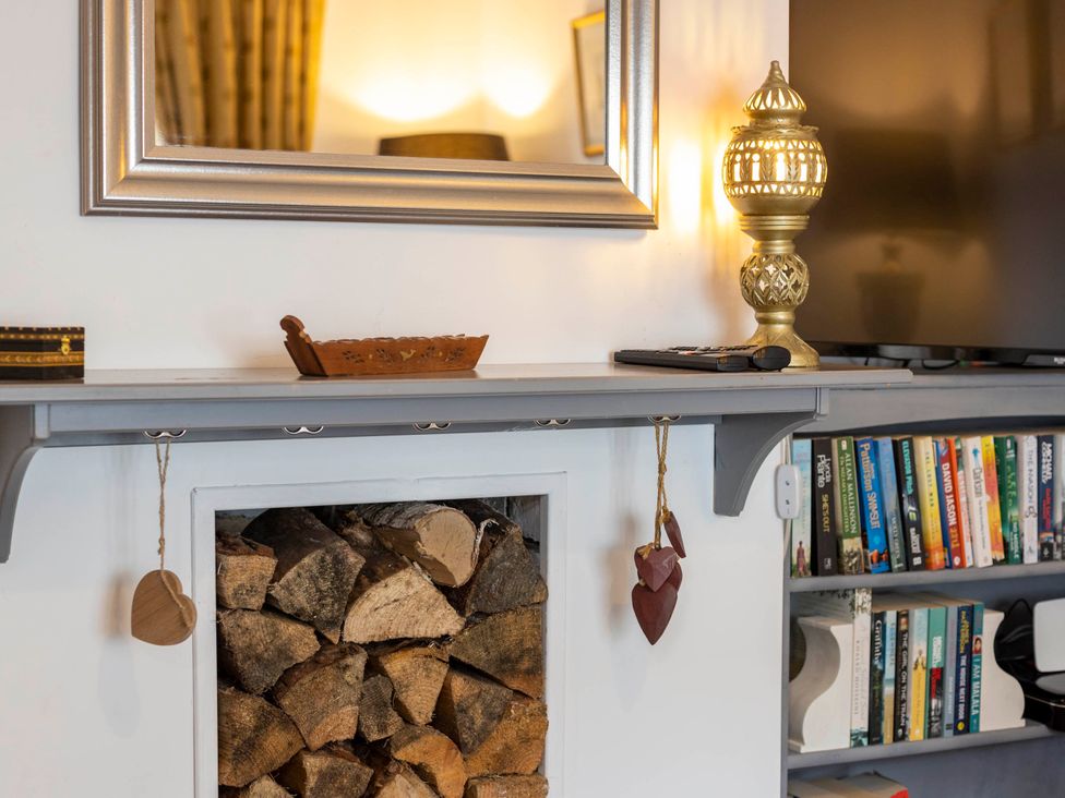 A living room with a fireplace and a shelf at Cozy Nook boutique Cottage in Oakham