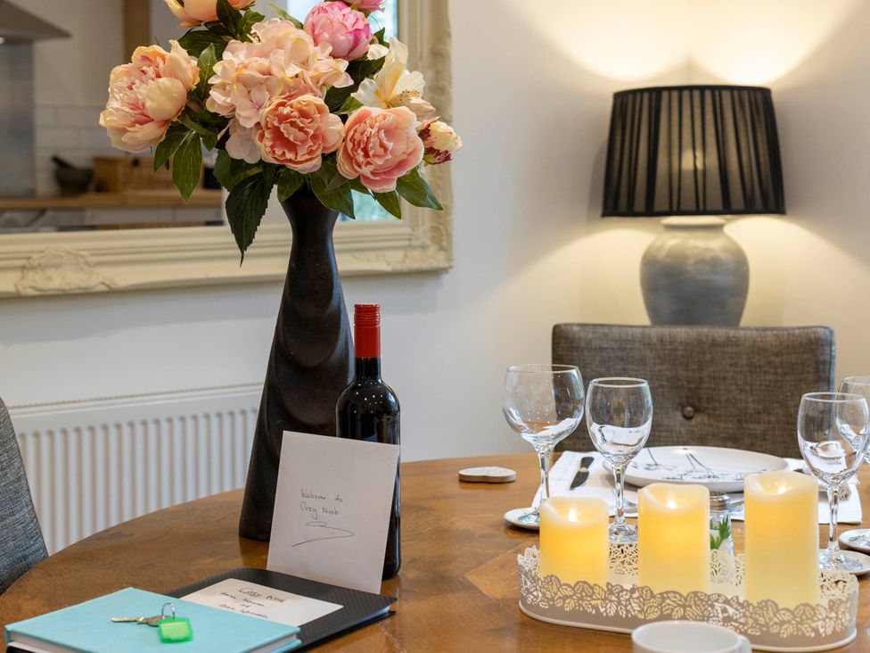 A dining room table set with flowers, wine, glasses, and candles at Cozy Nook boutique Cottage in Oakham