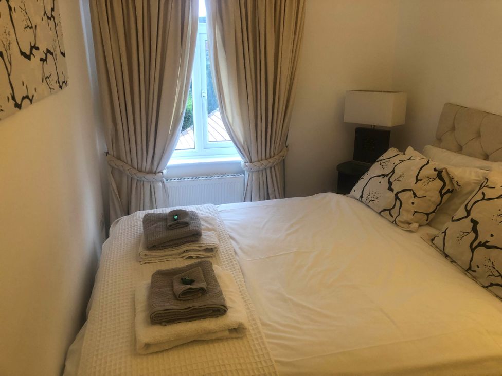 A bedroom with a bed, bedside table and curtains at Cozy Nook boutique Cottage in Oakham