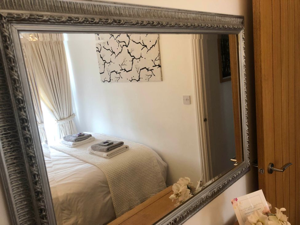 A bedroom with a mirror and towels on the bed at Cozy Nook boutique Cottage in Oakham