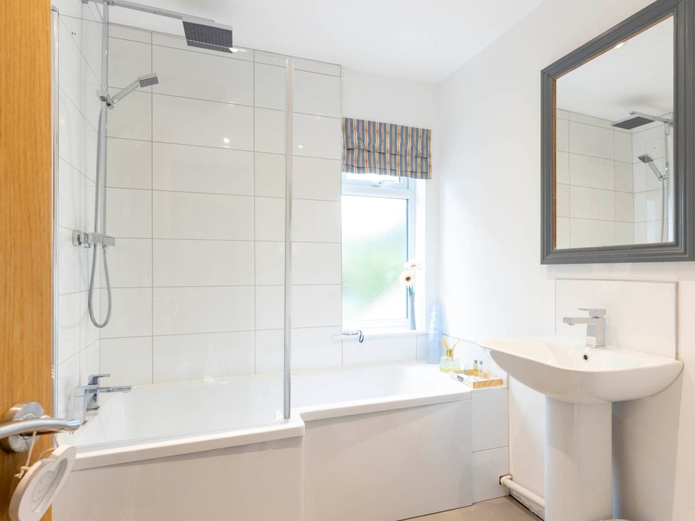 A bathroom with a bathtub, shower, sink and window at Cozy Nook boutique Cottage in Oakham