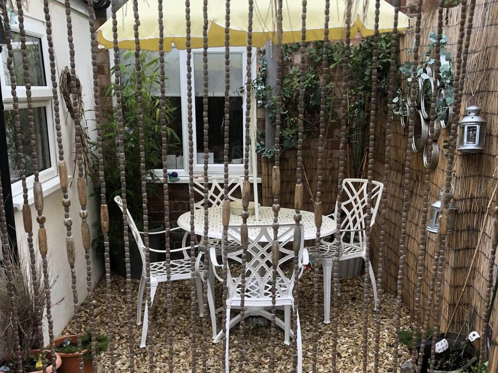A patio area with a table and chairs under an umbrella at Cozy Nook boutique Cottage in Oakham