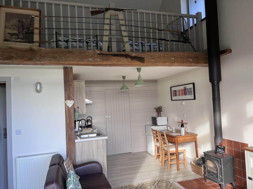 A living room with a sofa, table, refrigerator, and stove at Farmhouse Sleeps 5 Near Alton Towers Peak District, Shorwell