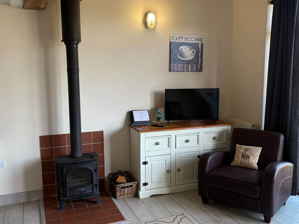 A living room with a stove and television stand at Farmhouse Sleeps 5 Near Alton Towers Peak District Shorwell