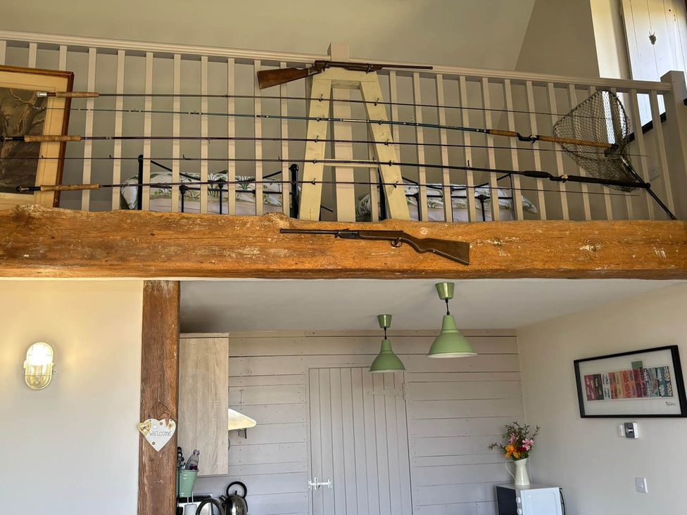 A living room with fishing rods and rifles displayed at Farmhouse Sleeps 5 Near Alton Towers Peak District in Shorwell