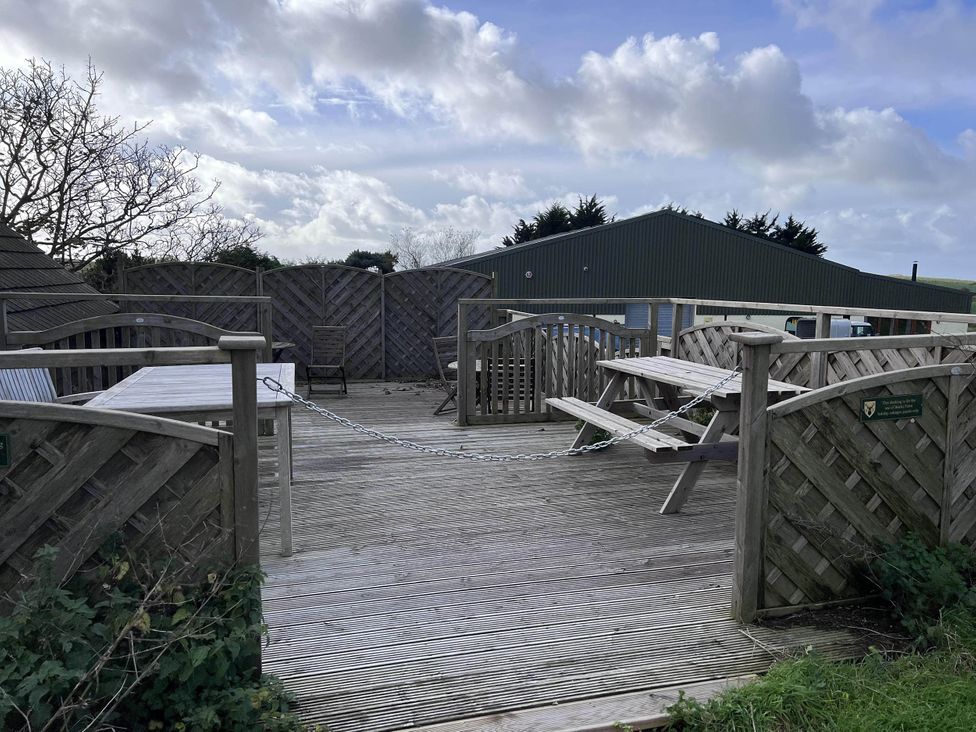 An outdoor area with wooden deck, tables, and chairs at Farmhouse Sleeps 5 Near Alton Towers Peak District, Shorwell