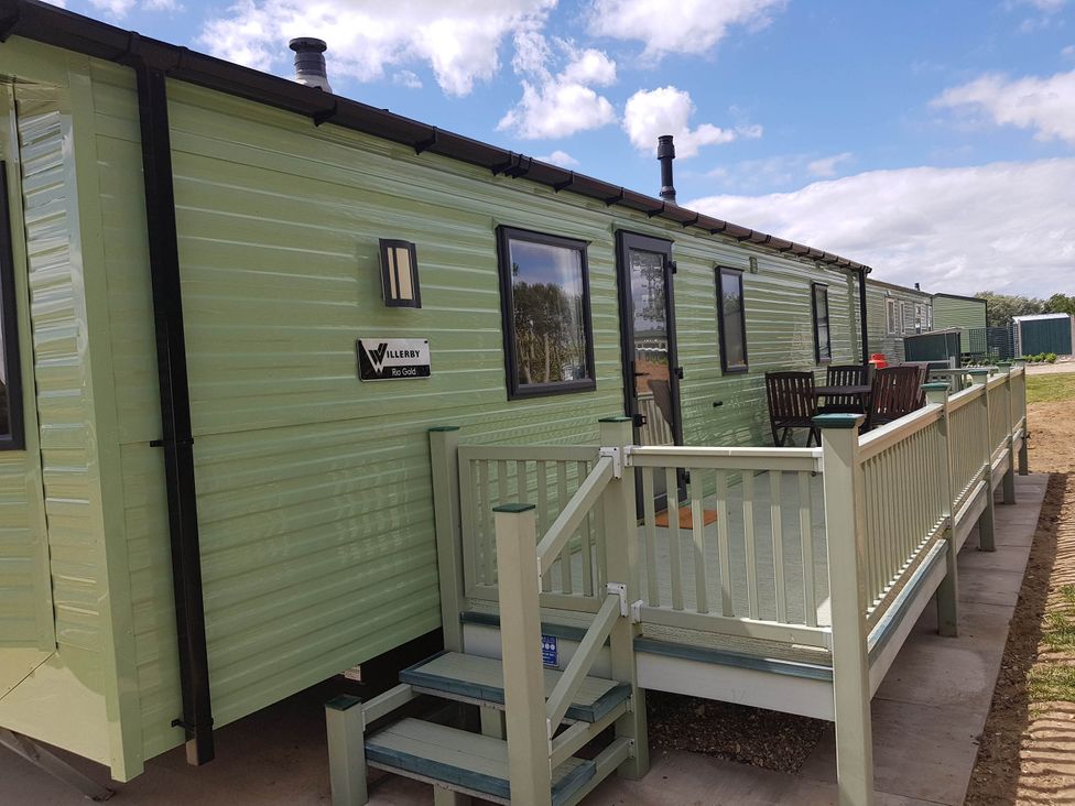A mobile home with a deck and stairs at Caravan Sleeps4 Pet friendly with Parking Available in Skegness