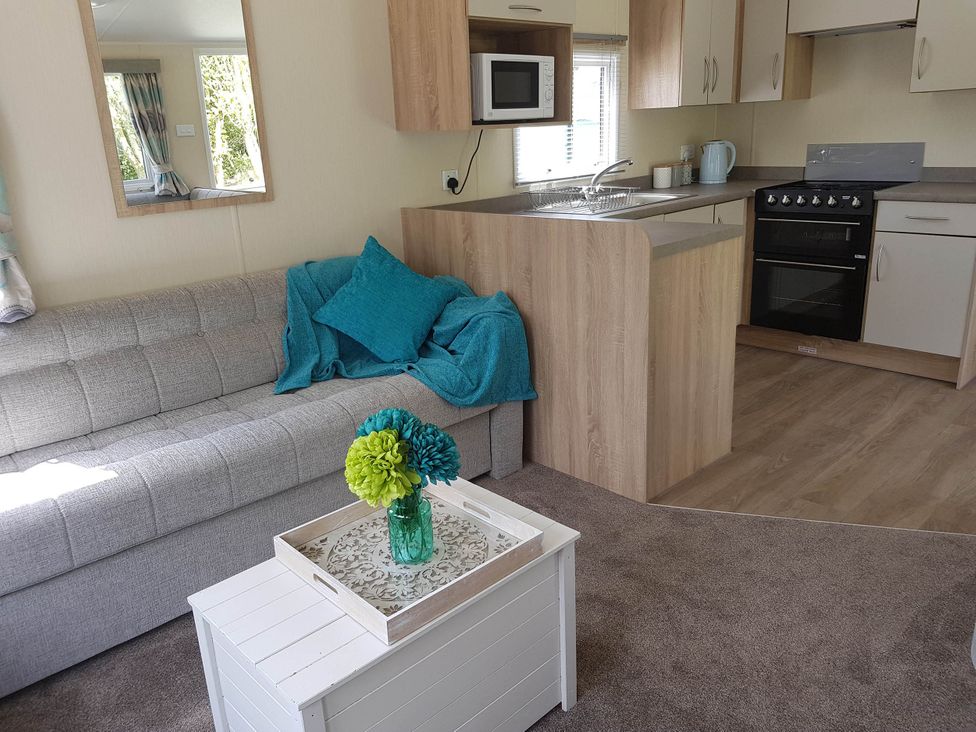 A living room with a sofa and a kitchen area at Caravan Sleeps4 Pet friendly with Parking Available in Skegness