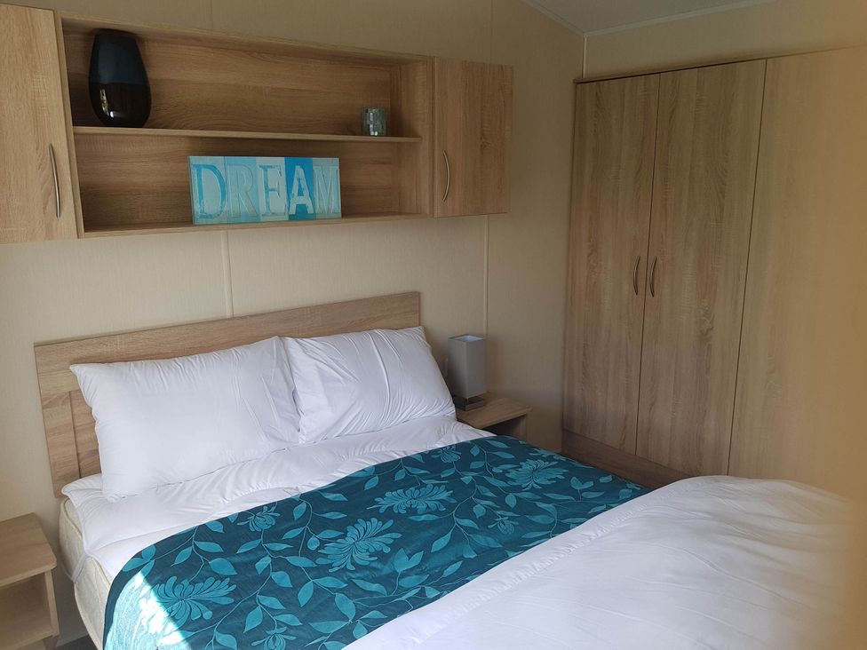 A bedroom with a bed and wardrobe at Caravan Sleeps4 Pet friendly with Parking Available in Skegness