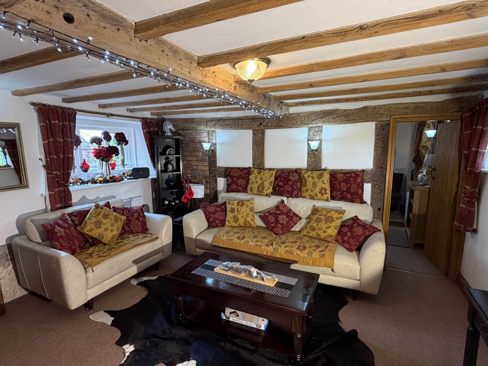 A living room with a sofa, coffee table, and brick wall at Farmhouse Sleeps 5 Near Alton Towers Peak District, Cheadle
