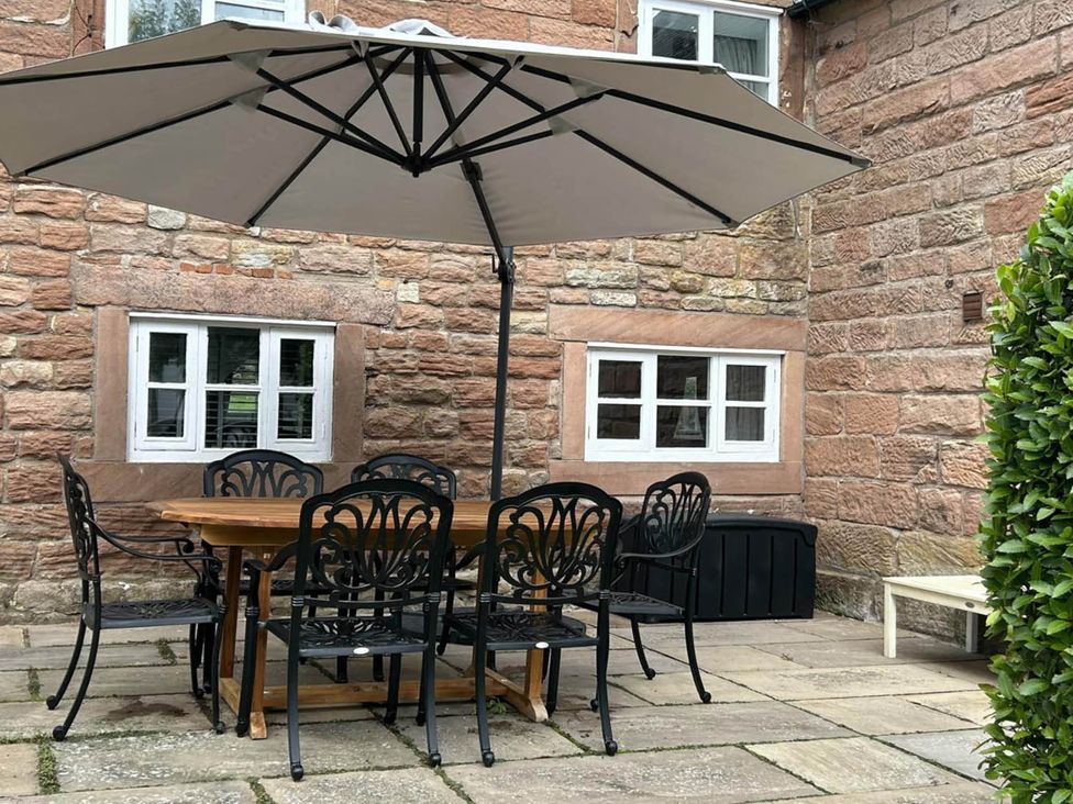 A garden with a table and chairs beneath an umbrella at Farmhouse Sleeps 5 Near Alton Towers Peak District, Cheadle