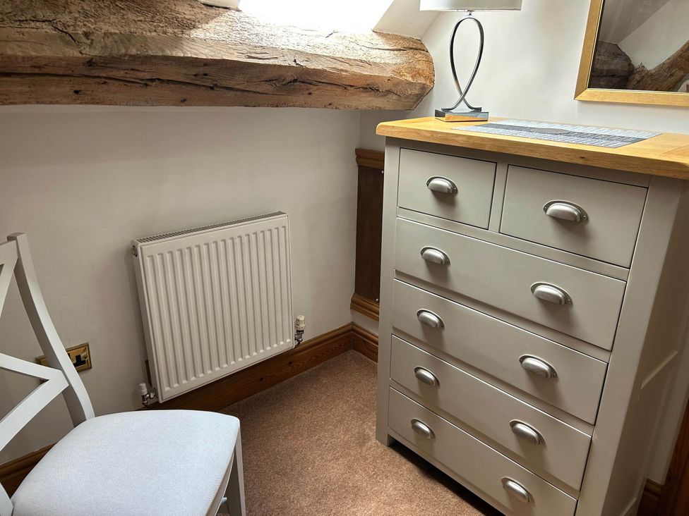 A bedroom with a dresser and lamp at Farmhouse Sleeps 5 Near Alton Towers Peak District, Cheadle