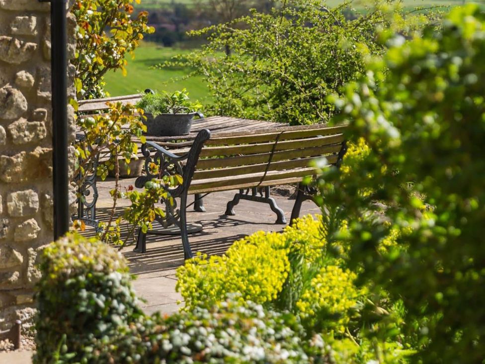 A garden with a bench and table at Stunning 3 Bedroom Cottage near Historic York Ampleforth