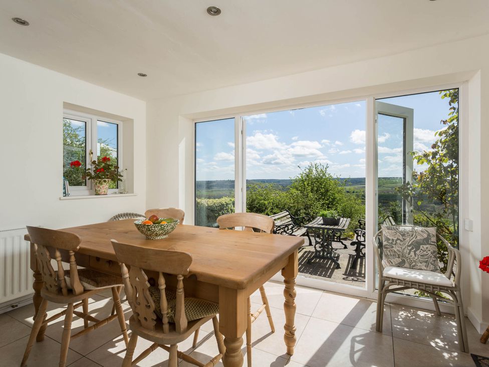 A dining room with a wooden table and chairs at Stunning 3 Bedroom Cottage near Historic York in Ampleforth