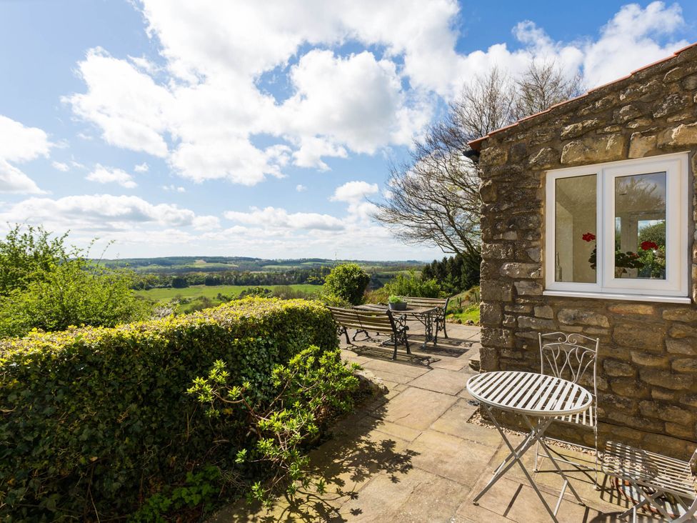 A patio with table and chairs overlooking a landscape at Stunning 3 Bedroom Cottage near Historic York