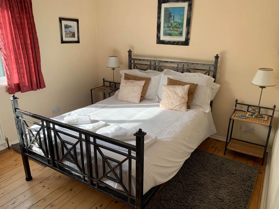 A bedroom with a bed, pillows, lamp, and nightstand at House Sleeps 8 Close to Beach Free parking, Mullion
