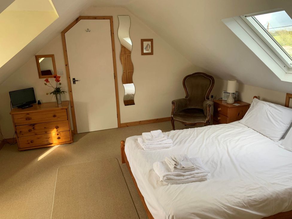 A bedroom with a bed and armchair at House Sleeps 8 Close to Beach Free parking in Mullion