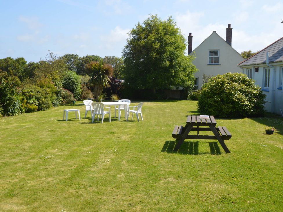 A garden with a table and chairs at House Sleeps 8 Close to Beach Free parking in Mullion
