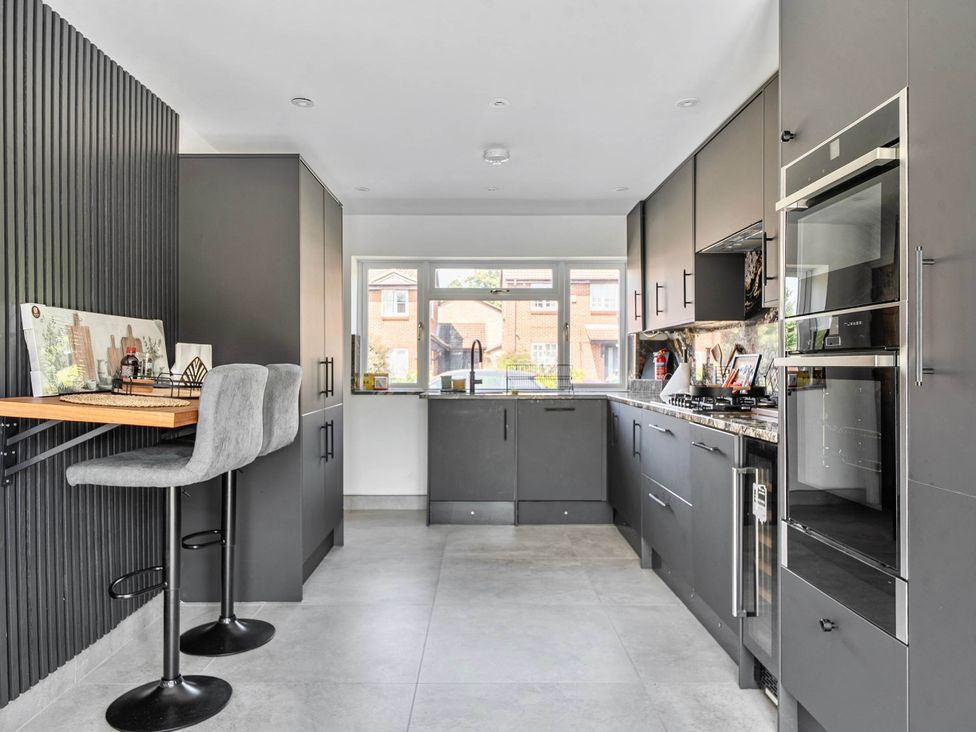 A kitchen with bar stools and kitchen appliances at Aylesbury Sleeps 6 Parking Central Location Aylesbeare