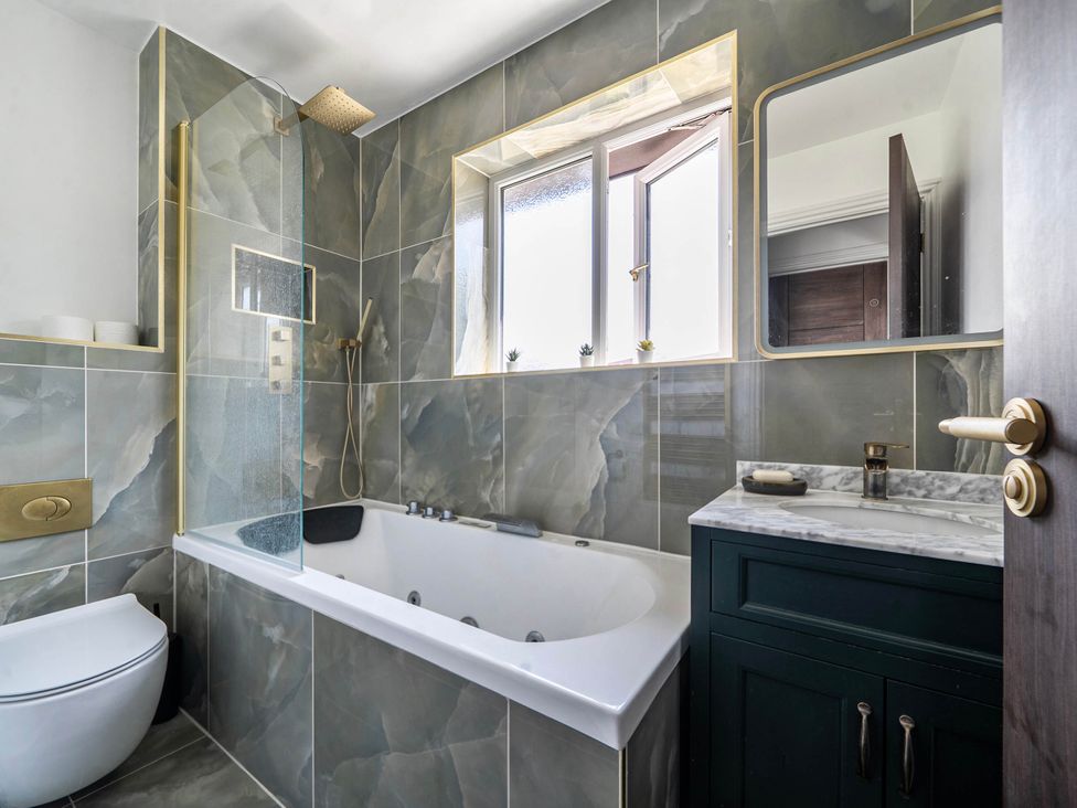 A bathroom with a bathtub, shower, and window at Aylesbury Sleeps 6 Parking Central Location Aylesbeare