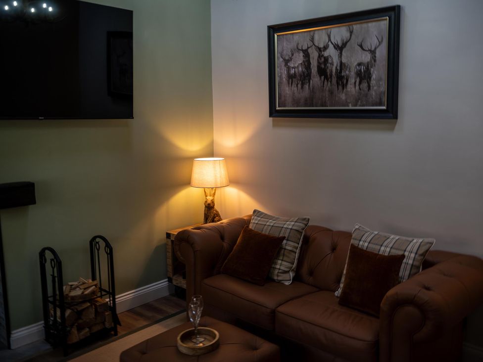 A living room with a sofa, lamp, and television at High Spec 1Bed Cottage in Staindrop